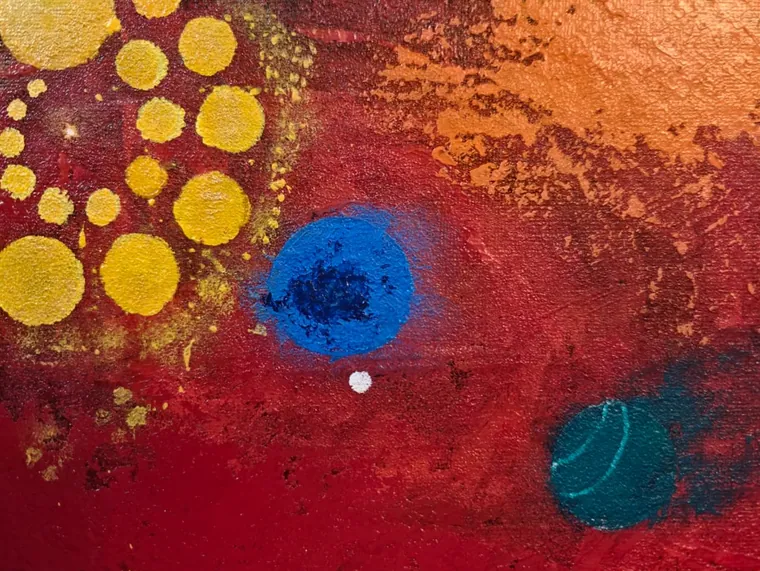 A glowing blue orb and a teal orb on a deep red field beside a cluster of yellow dots.