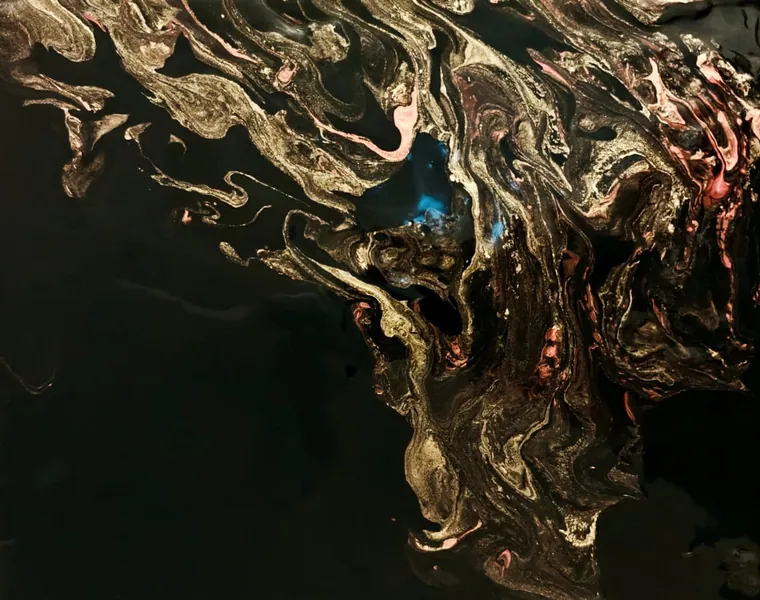 Gold, copper, and pink veins marbled across deep black with a small turquoise glow at the centre, like the fire caught in a black opal.