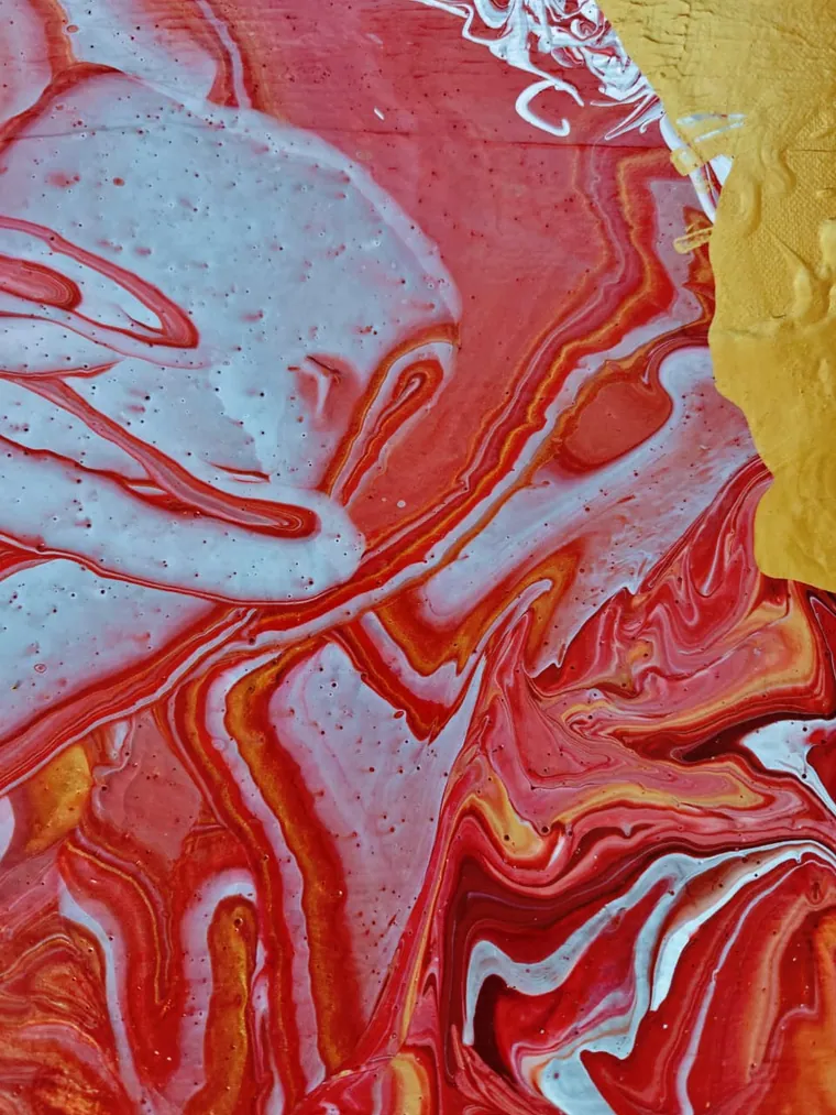 A turbulent pour of red, coral, white, and gold beside a block of ochre, churning like magma meeting ice.
