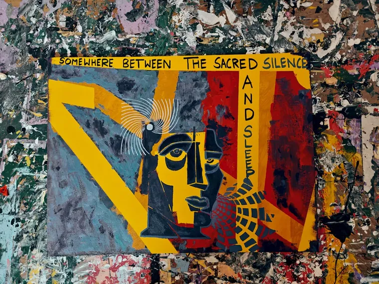 A modernist painting of a face built from flat angular planes of yellow, slate blue, deep red and black, with one large open eye and a smaller closed one, white lines radiating from a small moon-like disc at the left temple, and a fan of dark scalloped scales at the lower right. The words SOMEWHERE BETWEEN THE SACRED SILENCE are hand-lettered along the top edge and AND SLEEP runs vertically down the right side.